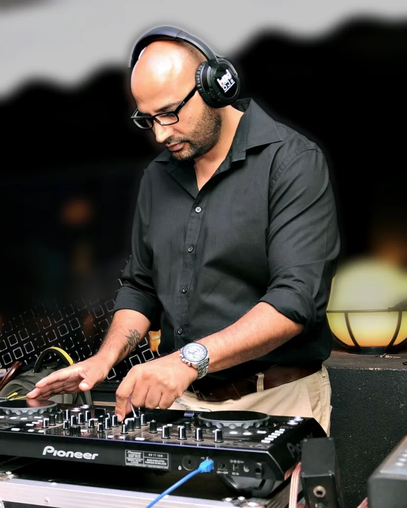 DJ RPM mixing under a marquee at an evening celebration